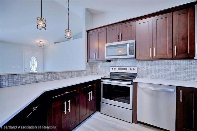 kitchen featuring lofted ceiling, hanging light fixtures, stainless steel appliances, tasteful backsplash, and light wood-type flooring