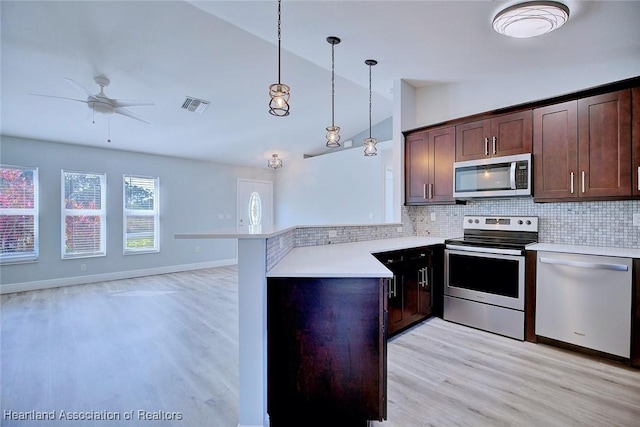 kitchen featuring stainless steel appliances, decorative light fixtures, kitchen peninsula, and backsplash