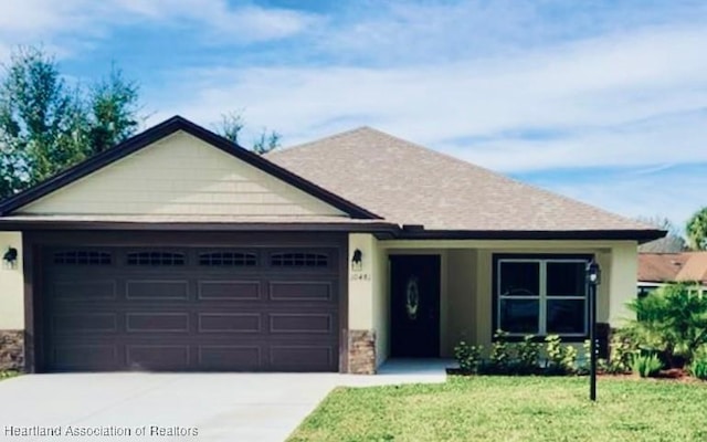 ranch-style house with an attached garage, concrete driveway, stone siding, roof with shingles, and a front lawn