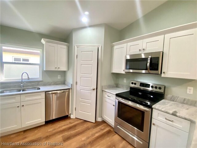 kitchen featuring sink, white cabinets, light hardwood / wood-style floors, and appliances with stainless steel finishes