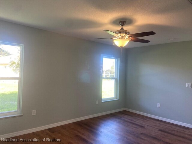 empty room with ceiling fan and dark hardwood / wood-style flooring