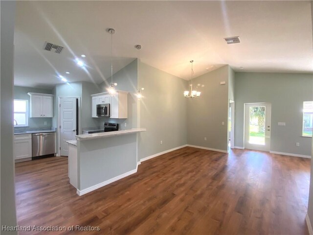 kitchen featuring white cabinetry, hanging light fixtures, stainless steel appliances, dark hardwood / wood-style floors, and a notable chandelier