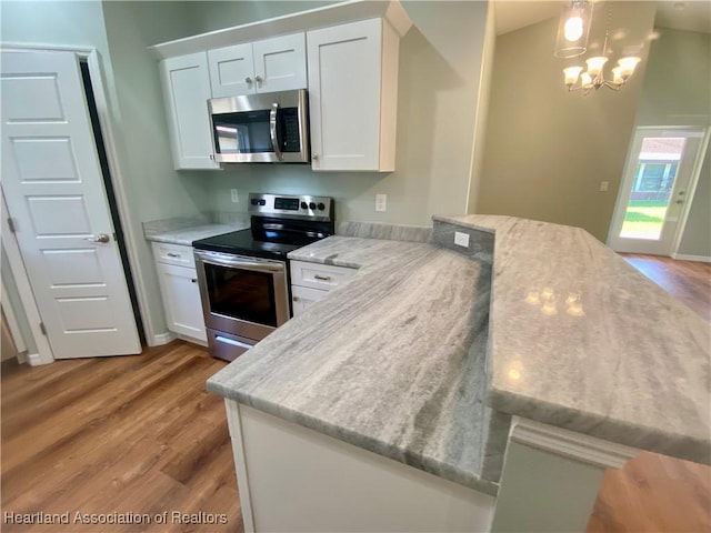 kitchen featuring stainless steel appliances, light wood-type flooring, white cabinetry, and light stone counters