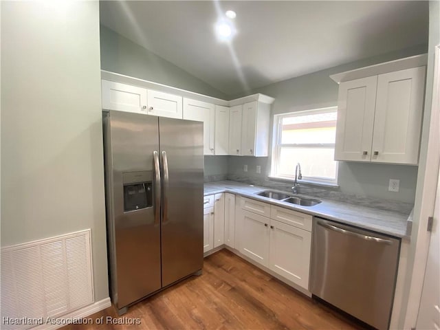 kitchen with visible vents, white cabinetry, stainless steel appliances, and a sink