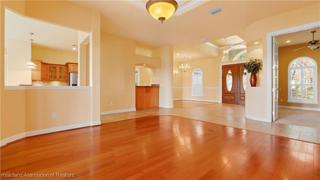 interior space with baseboards, ceiling fan with notable chandelier, visible vents, and light wood-style floors