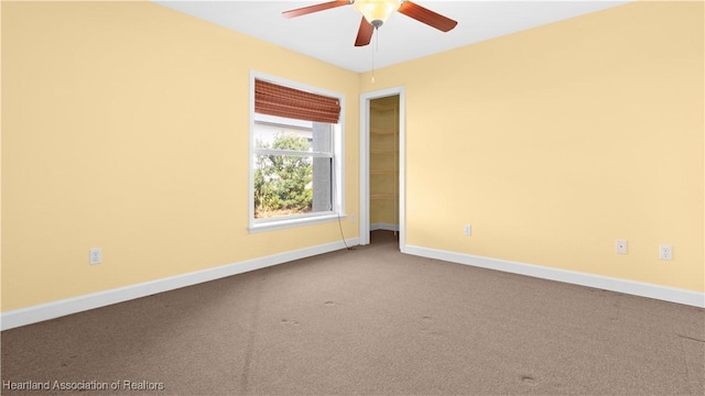 carpeted empty room with a ceiling fan and baseboards