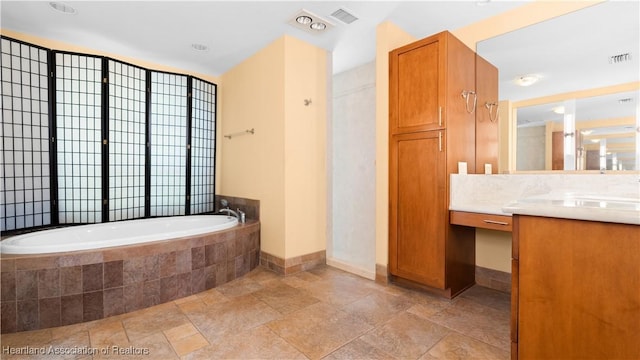 bathroom featuring stone finish flooring, visible vents, vanity, and a bath