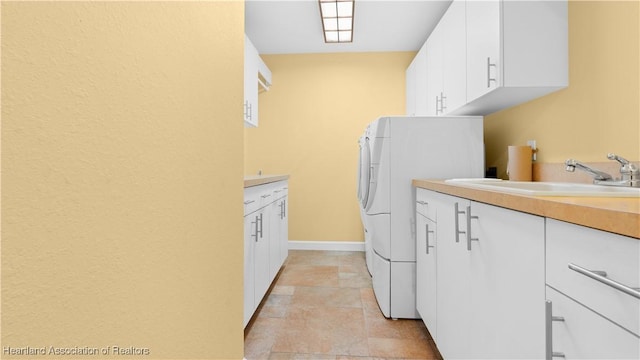 laundry room with washer / dryer, a sink, cabinet space, and baseboards