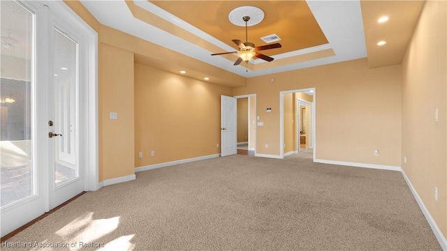 carpeted empty room with baseboards, visible vents, a ceiling fan, a tray ceiling, and recessed lighting