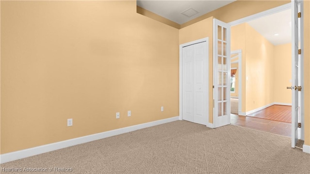 unfurnished bedroom with visible vents, baseboards, carpet, french doors, and a closet