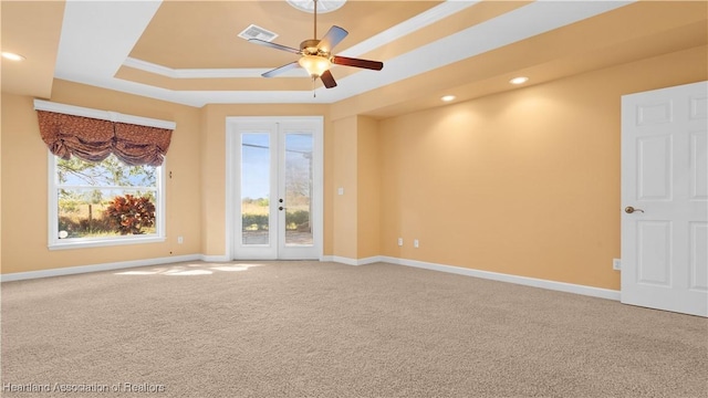 spare room with a raised ceiling, carpet flooring, visible vents, and baseboards