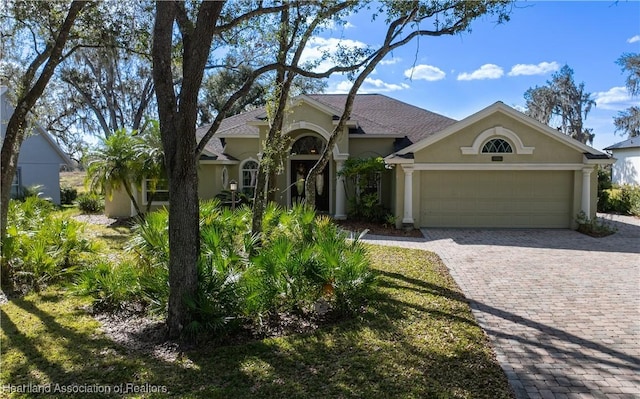 view of front facade with decorative driveway, an attached garage, and stucco siding