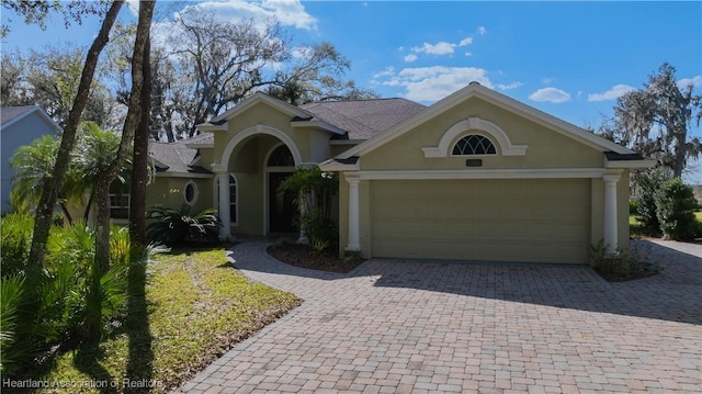 view of front of property featuring a garage, decorative driveway, and stucco siding