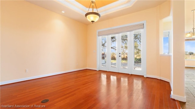 entryway with ornamental molding, a tray ceiling, baseboards, and wood finished floors