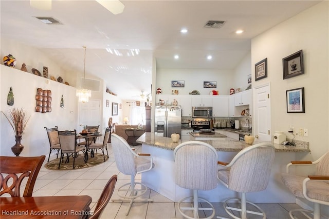 kitchen featuring light tile patterned floors, a breakfast bar area, appliances with stainless steel finishes, white cabinetry, and kitchen peninsula