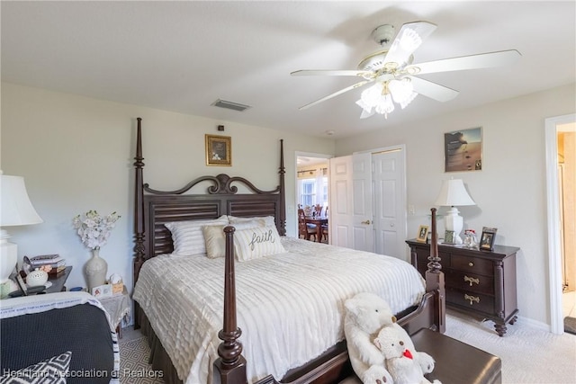 carpeted bedroom with ensuite bath, a closet, and ceiling fan