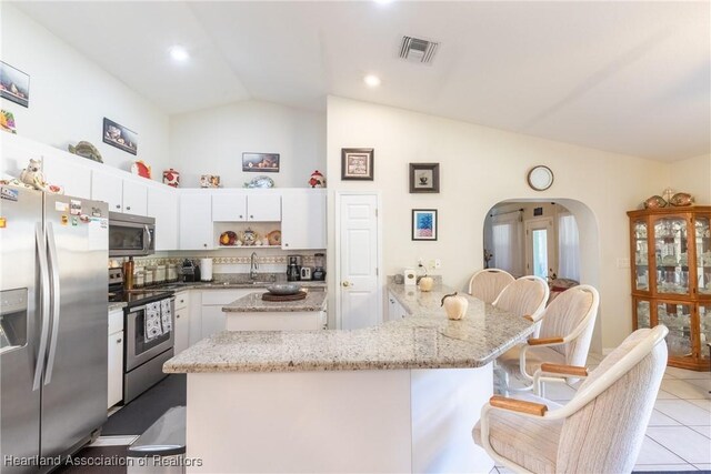 kitchen with stainless steel appliances, light stone countertops, sink, and white cabinets