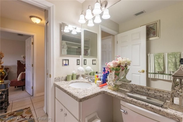 bathroom with vanity, toilet, tile patterned flooring, and a notable chandelier