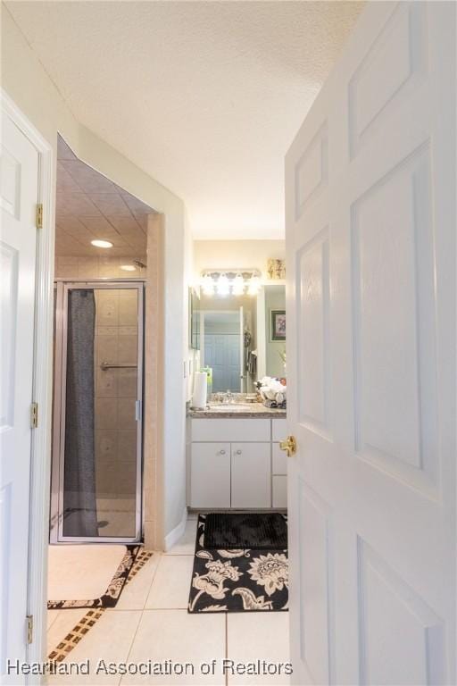 bathroom featuring vanity, a shower with shower door, and tile patterned floors