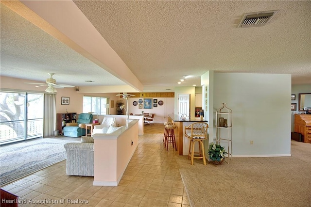 living area with a textured ceiling, visible vents, a ceiling fan, and light tile patterned floors