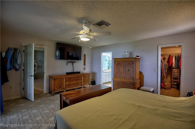 bedroom with a textured ceiling, a walk in closet, a closet, and visible vents