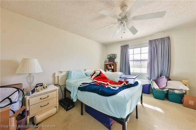 bedroom with a textured ceiling, light colored carpet, and ceiling fan