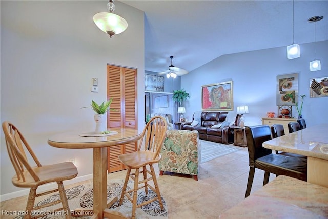 dining space with ceiling fan, light tile patterned floors, and vaulted ceiling