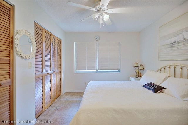 bedroom with a textured ceiling, a closet, light tile patterned floors, and ceiling fan