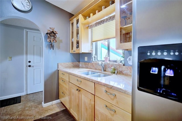 kitchen with light stone countertops, sink, light brown cabinets, and stainless steel fridge with ice dispenser