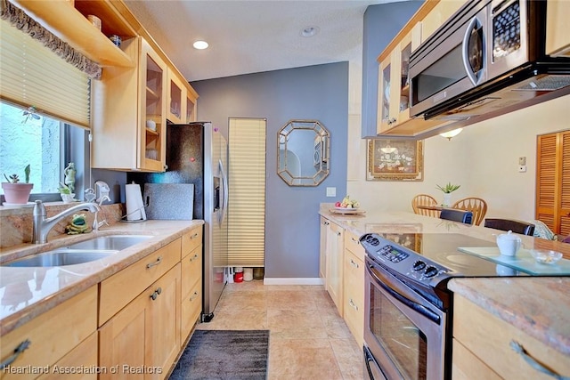 kitchen featuring appliances with stainless steel finishes, light tile patterned flooring, light brown cabinetry, light stone countertops, and sink