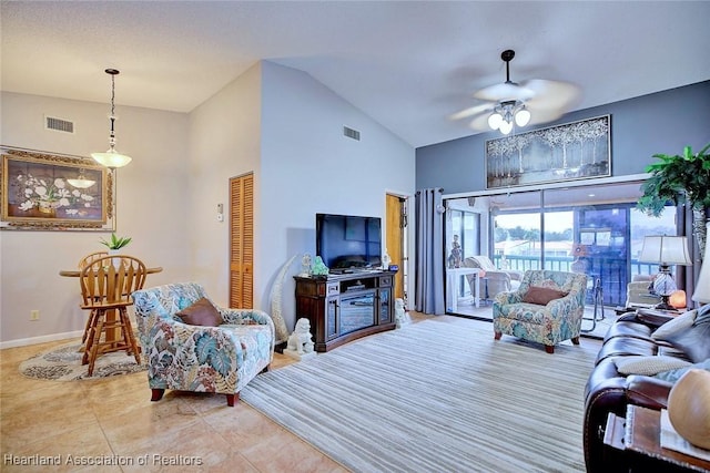 living room featuring ceiling fan, light tile patterned floors, and vaulted ceiling