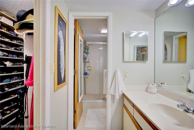 bathroom with tile patterned flooring, a shower with shower door, and vanity