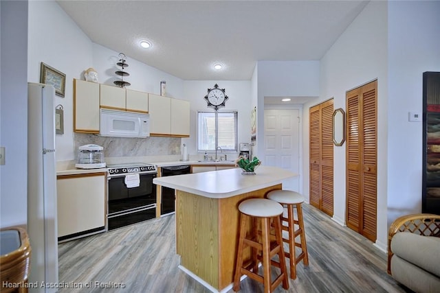 4915 Casablanca Cir Unit H22, Sebring, FL 33870 - kitchen with black appliances, light wood-style floors, light countertops, and a kitchen breakfast bar
