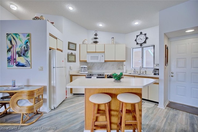 4915 Casablanca Cir Unit H22, Sebring, FL 33870 - kitchen with white appliances, a sink, light countertops, light wood-style floors, and a kitchen bar