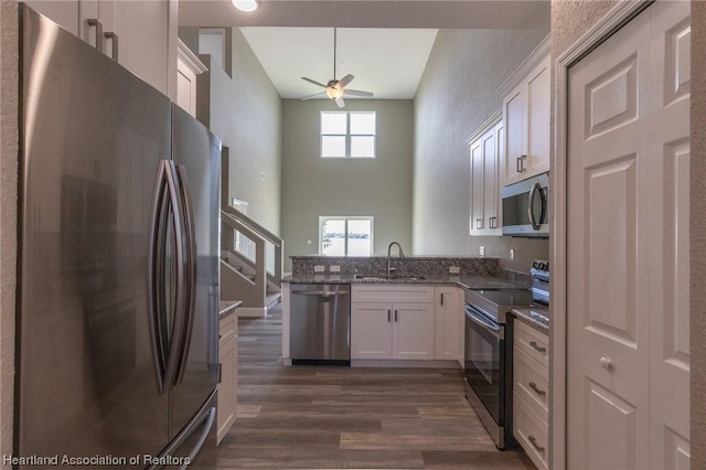 kitchen with high vaulted ceiling, white cabinets, sink, ceiling fan, and appliances with stainless steel finishes