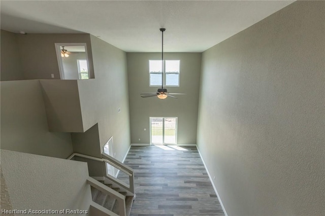 interior space with ceiling fan, a towering ceiling, and hardwood / wood-style flooring