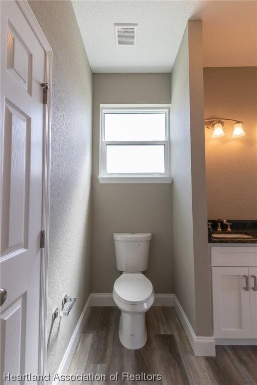 bathroom featuring toilet, vanity, a textured ceiling, and hardwood / wood-style flooring