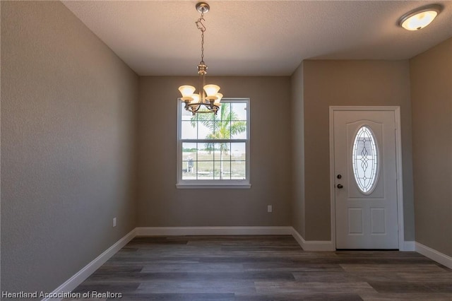 foyer featuring dark wood-type flooring, a textured ceiling, and a notable chandelier