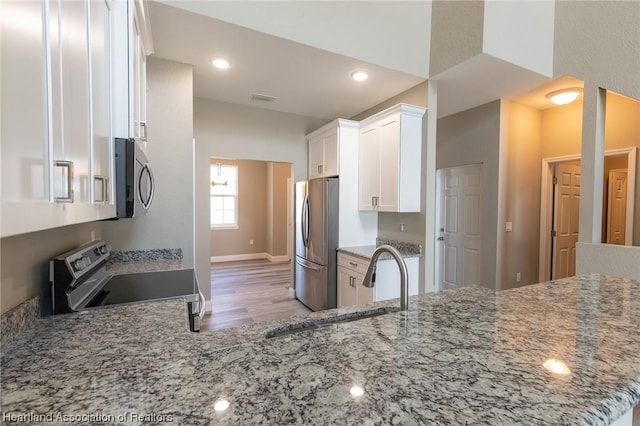 kitchen featuring light stone countertops, sink, stainless steel appliances, kitchen peninsula, and white cabinets