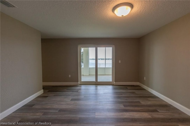 spare room with dark hardwood / wood-style flooring and a textured ceiling