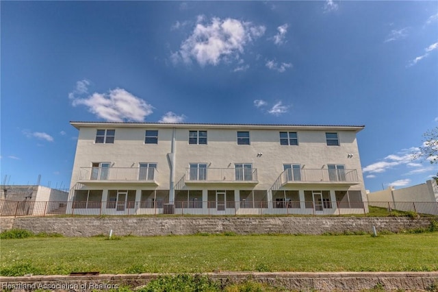 rear view of house with a lawn and a balcony