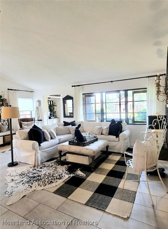 2919 Summertree Dr, Sebring, FL 33872 - living room featuring light tile patterned flooring, vaulted ceiling, and plenty of natural light