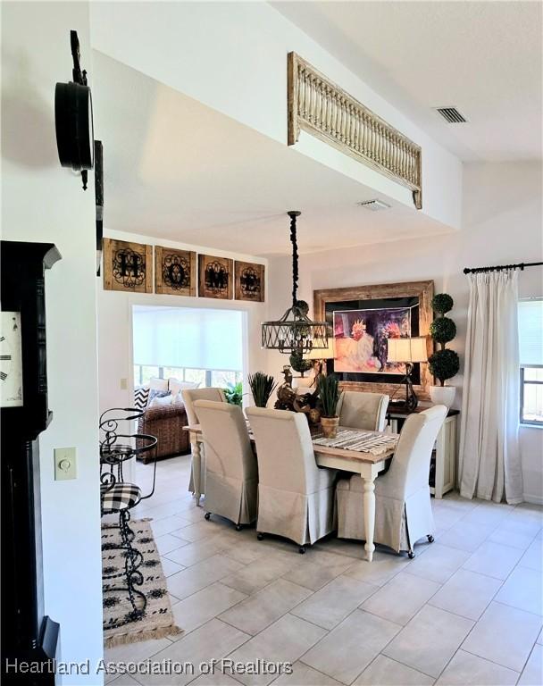 2919 Summertree Dr, Sebring, FL 33872 - dining area with visible vents, a towering ceiling, a notable chandelier, and light tile patterned flooring