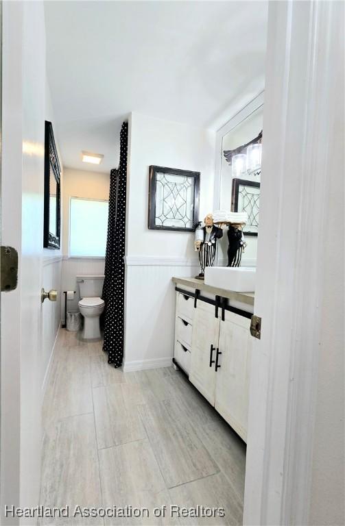 2919 Summertree Dr, Sebring, FL 33872 - bathroom with a wainscoted wall, vanity, and toilet