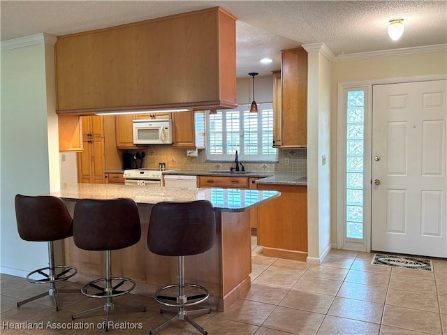 kitchen with a kitchen breakfast bar, white appliances, kitchen peninsula, and a textured ceiling