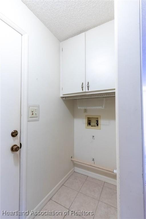 washroom with light tile patterned floors, cabinets, a textured ceiling, and washer hookup