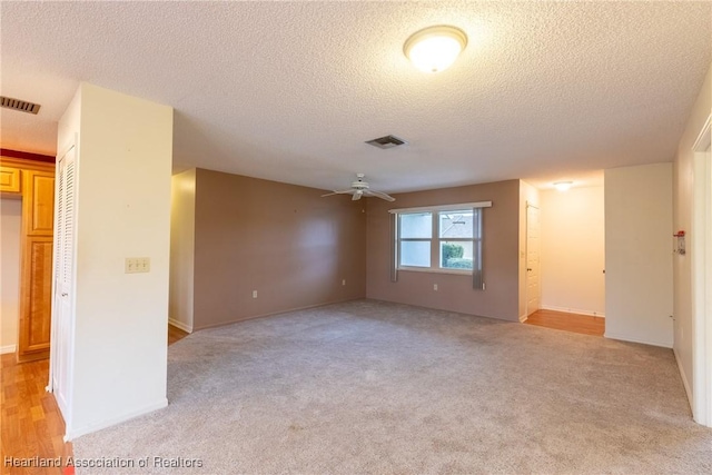 carpeted empty room featuring ceiling fan and a textured ceiling