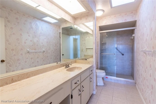 bathroom with tile patterned floors, vanity, toilet, and a shower with door