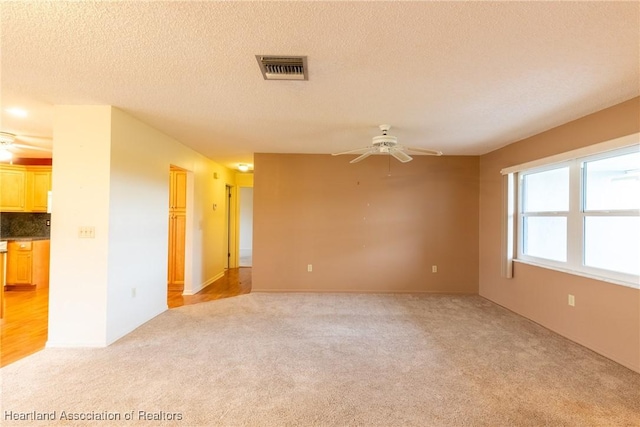 carpeted empty room with ceiling fan and a textured ceiling