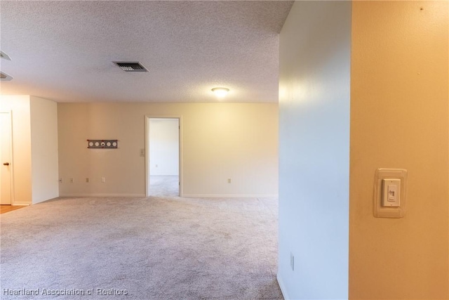 carpeted empty room featuring a textured ceiling